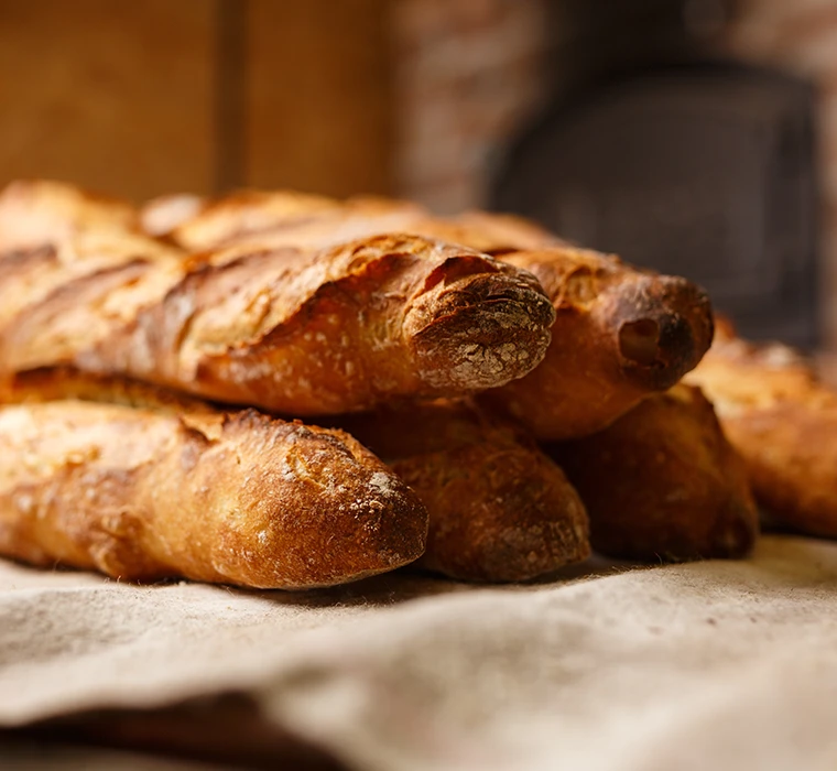 Mehrere, knusprige Baguettes gestapelt auf einem Leinentuch