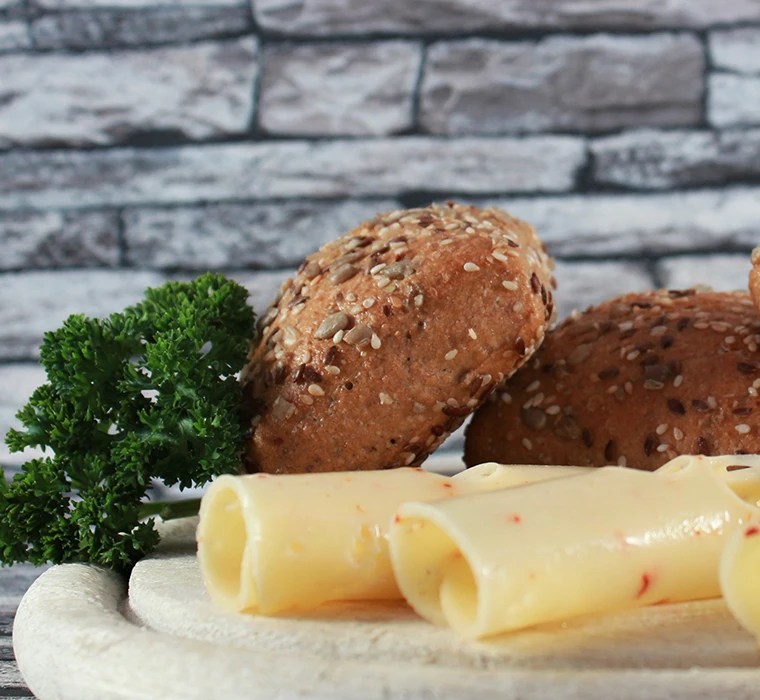 Brötchen auf einem Schneidebrett mit Käse und Kräutern dekoriert