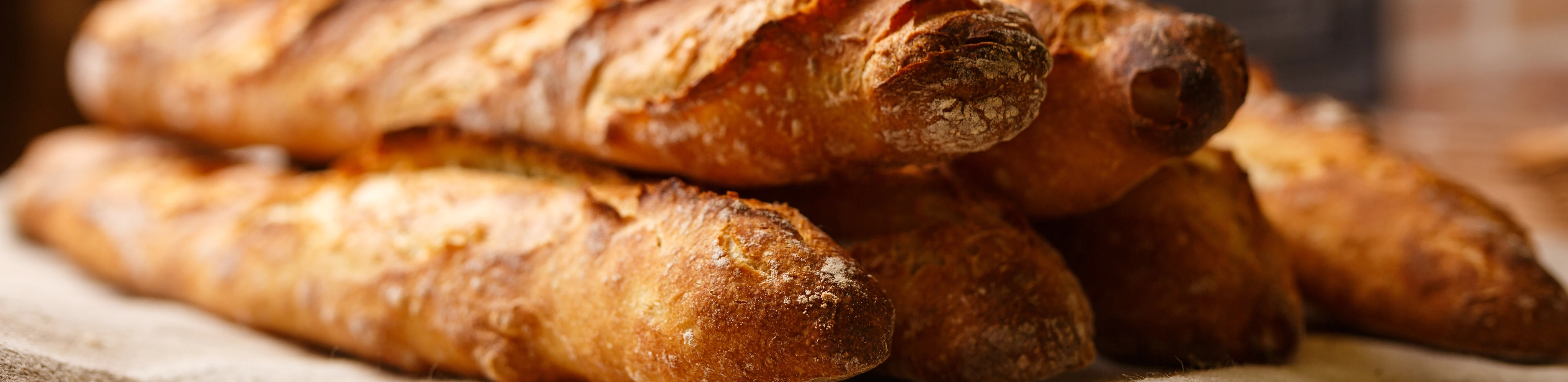 Mehrere, knusprige Baguettes gestapelt auf einem Leinentuch