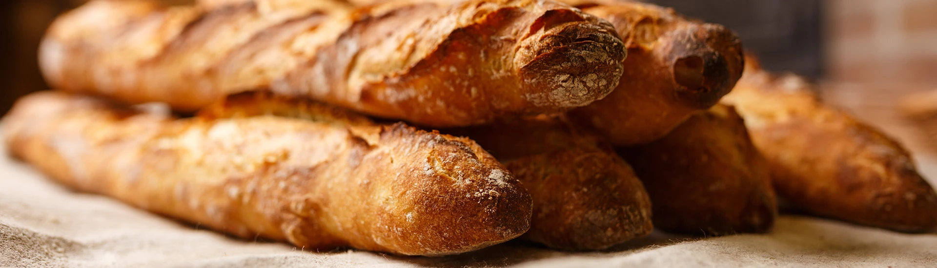 Mehrere, knusprige Baguettes gestapelt auf einem Leinentuch